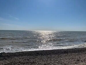 A beach with a pebbly shore and calm sea under a clear sky. - The Hollies (Walmer)