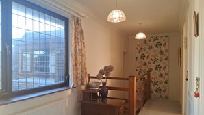 A hallway with a radiator, a wooden bench, a vase with flowers, and a staircase. - The Hollies (Walmer)