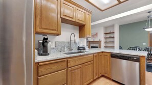 A kitchen with wooden cabinets, a stainless steel dishwasher, a coffee maker, and a granite countertop. - Evergreen Haven - Spacious Retreat Near the Best of Eugene (Eugene)