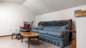 A living room with a blue sofa, a wooden chair, a wooden coffee table, and a patterned rug. - Evergreen Haven - Spacious Retreat Near the Best of Eugene (Eugene)