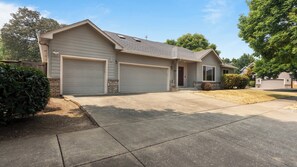 A single-story house with a garage, a front porch, and a driveway. - Evergreen Haven - Spacious Retreat Near the Best of Eugene (Eugene)