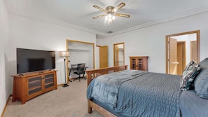 A bedroom with a bed, a TV, a desk, and a wardrobe.