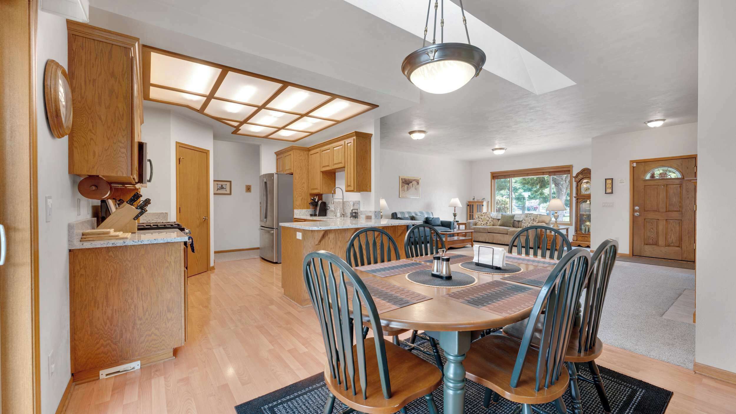 A spacious kitchen with wooden cabinets, a central island, and a dining area with a round table and chairs.