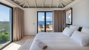 A hotel room with a large bed, a view of the ocean, and a balcony. - Villa Scarlett (4 bedrooms) (Saint Barthélemy)