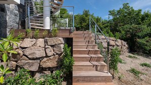 A spiral staircase leading to a modern building with a stone wall and greenery around. - Villa Scarlett (4 bedrooms) (Saint Barthélemy)