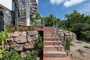 A spiral staircase leading to a modern building with a stone wall and greenery around. - Villa Scarlett (4 bedrooms) (Saint Barthélemy)
