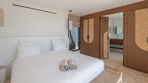 A modern bedroom with a large bed, a wooden wardrobe, and a bathroom visible through an open door. - Villa Scarlett (4 bedrooms) (Saint Barthélemy)