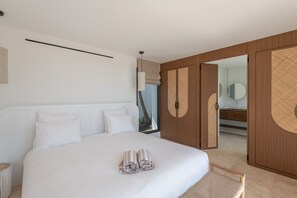 A modern bedroom with a large bed, a wooden wardrobe, and a bathroom visible through an open door. - Villa Scarlett (4 bedrooms) (Saint Barthélemy)