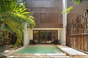 A pool area with a wooden fence, a palm tree, and a view of the surrounding greenery. - Your Home in the Mayan Jungle (Tulum)