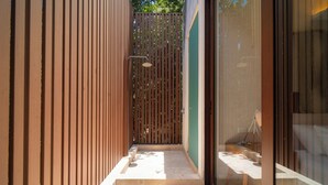 A modern bathroom with a shower, a glass door, and a tiled floor. - Your Home in the Mayan Jungle (Tulum)