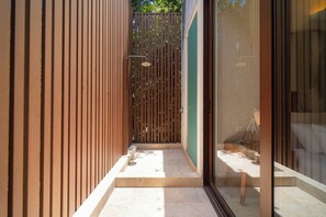 A modern bathroom with a shower, a glass door, and a tiled floor. - Your Home in the Mayan Jungle (Tulum)