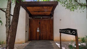 A wooden entrance with a sign reading 'OJEJOS SOCIALES' leading to a door. - Your Home in the Mayan Jungle (Tulum)