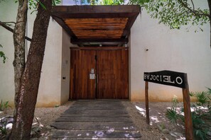 A wooden entrance with a sign reading 'OJEJOS SOCIALES' leading to a door. - Your Home in the Mayan Jungle (Tulum)