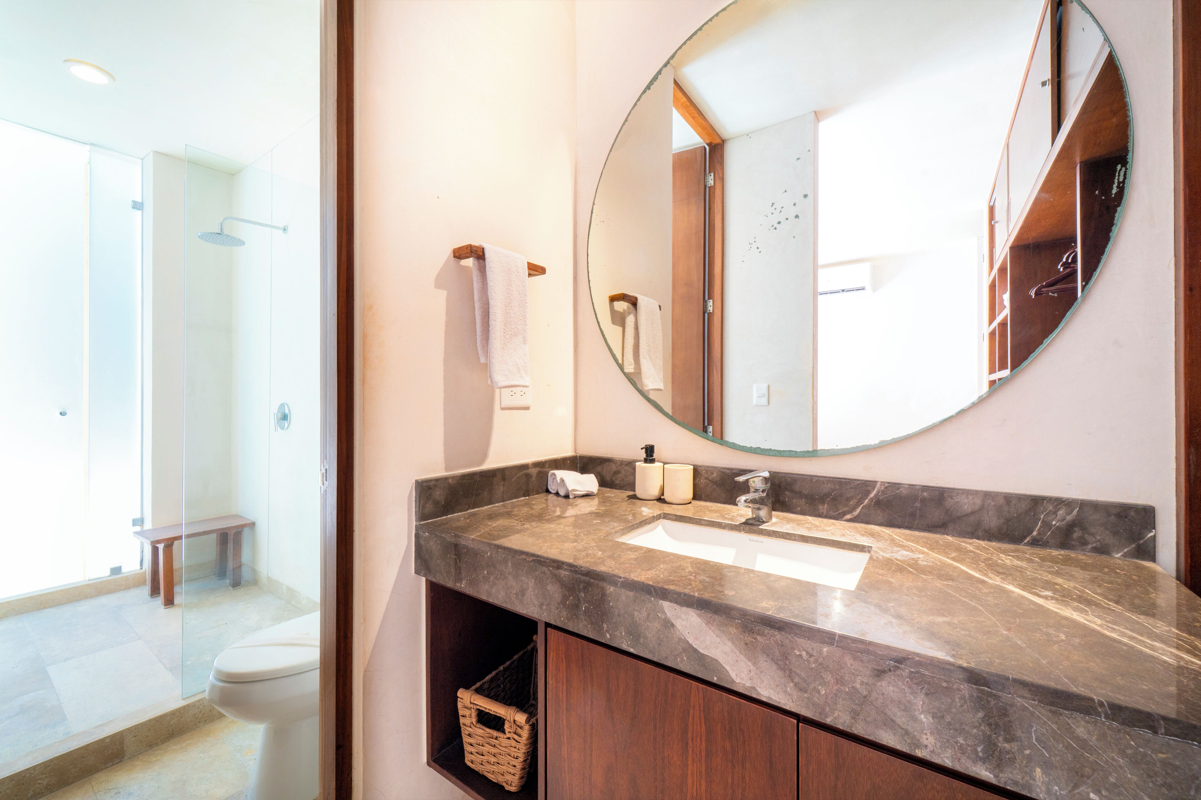 A bathroom with a marble sink, a large mirror, and a wooden cabinet.