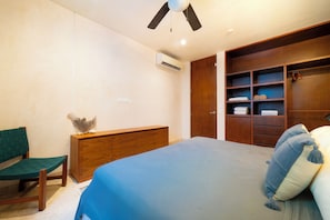 A bedroom with a bed, a wooden dresser, a bench, and a built-in wardrobe with shelves. - Your Home in the Mayan Jungle (Tulum)