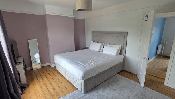 A bedroom with a large bed, a bedside table, a mirror, and a wardrobe. - West Acre Cottage - sleeps 5 guests in 3 bedrooms (Westacre)