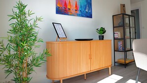 Una habitación con un armario de madera, una planta en maceta, un cuadro de colores y una estantería.