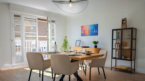 Un comedor con una mesa de madera, cuatro sillas, una planta en maceta y una estantería.