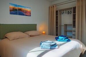Ein Hotelzimmer mit Bett, Nachttisch, Lampe, Kleiderschrank und einem Bild an der Wand.