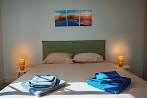 A hotel room with a bed, two bedside lamps, a green headboard, two pillows, and a wall with three paintings. - 10 minutes from the beach and Nausicaá, 76 m² apartment + motorcycle garage available upon request. (Boulogne-sur-Mer)