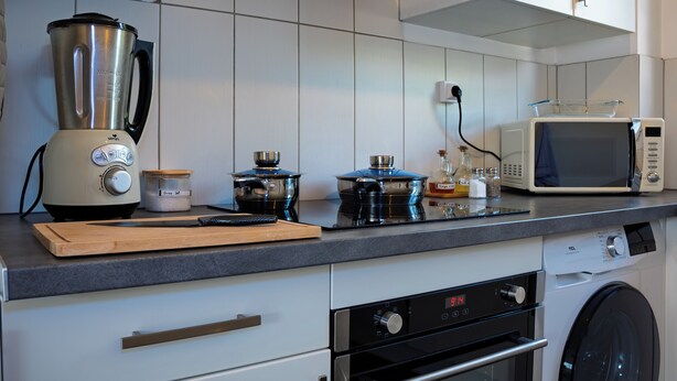 Una cocina moderna con horno empotrado, microondas y cafetera.