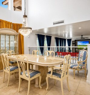 A dining area with a large table, chairs, a chandelier, and a view of the outdoors. - Luxury 5BR Retreat with Private Pool in Buckeye (Buckeye)