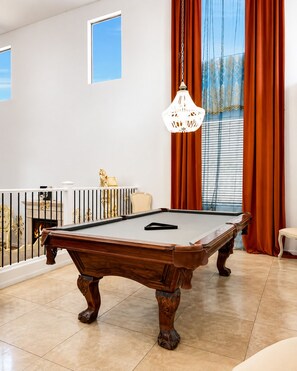 A pool table in a room with a balcony, a fireplace, and a chandelier. - Luxury 5BR Retreat with Private Pool in Buckeye (Buckeye)