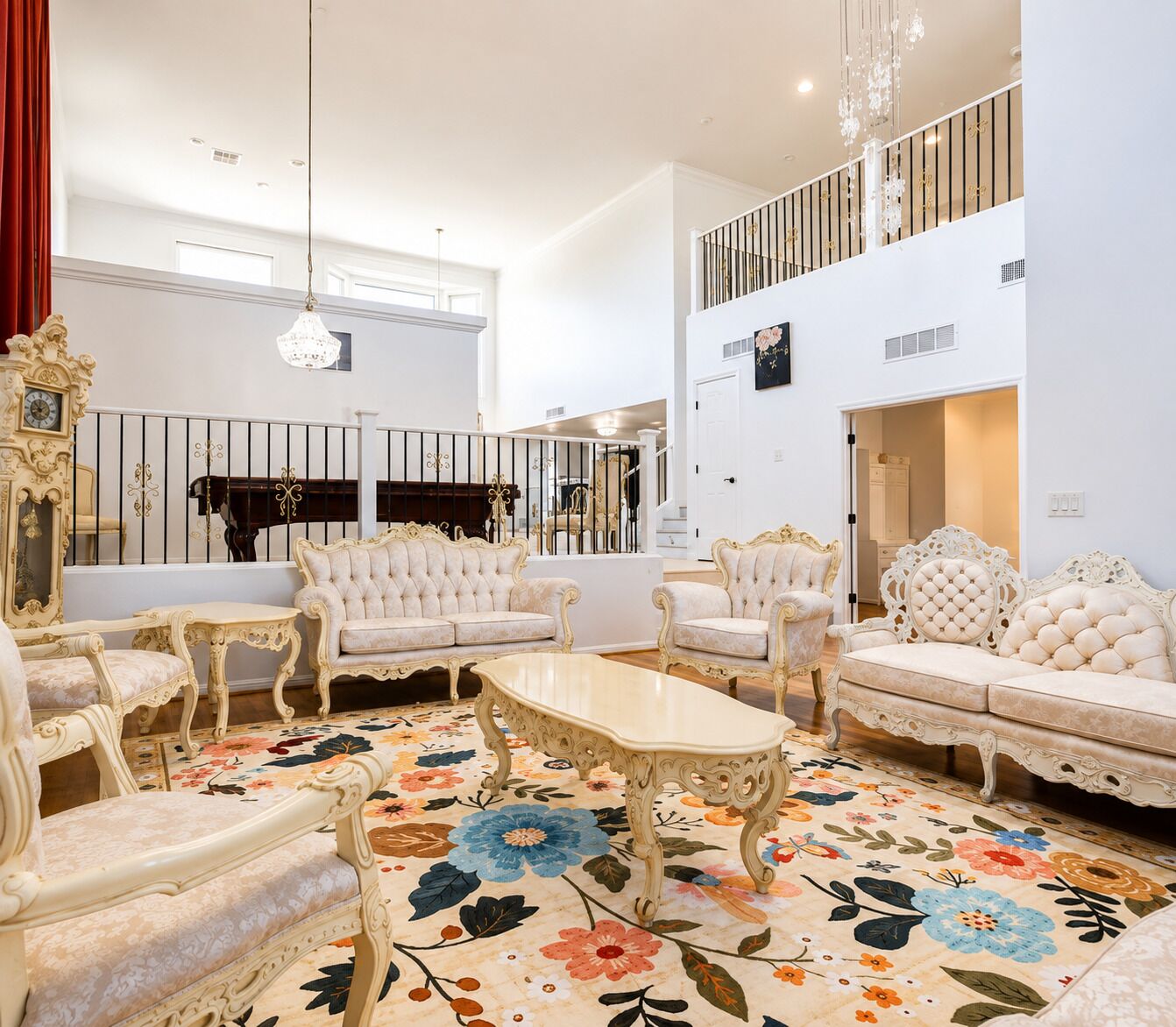 A spacious living room with ornate furniture, a large floral rug, and a staircase leading to an upper level.