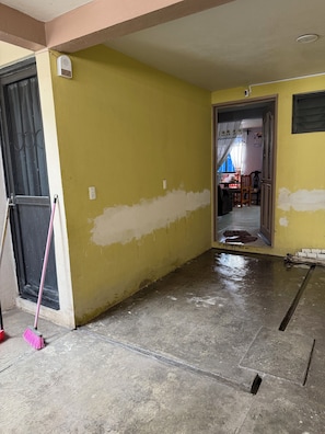 A hallway with a yellow wall, a black door, and a pink broom leaning against the wall.