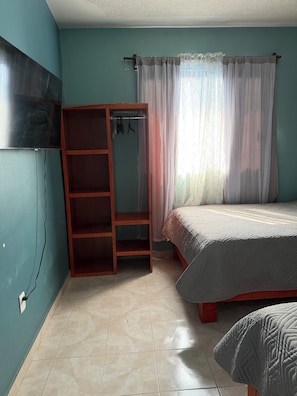 A bedroom with a bed, a wardrobe, and a television on the wall. - Spacious two-story house with three bedrooms and two bathrooms in an excellent location. (Ecatepec de Morelos. Eso. De Mexico)