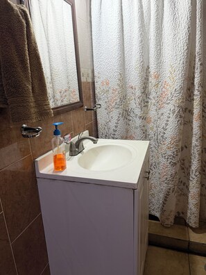 A bathroom with a white sink, a mirror, a towel rack, and a shower curtain.