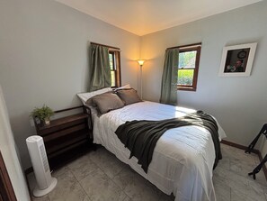 A bedroom with a bed, bedside table, lamp, and a wall-mounted picture.