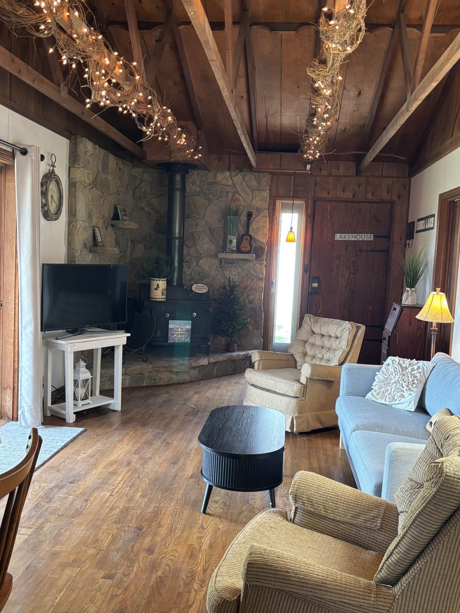 A cozy living room with a stone wall, a fireplace, a television, and comfortable seating.