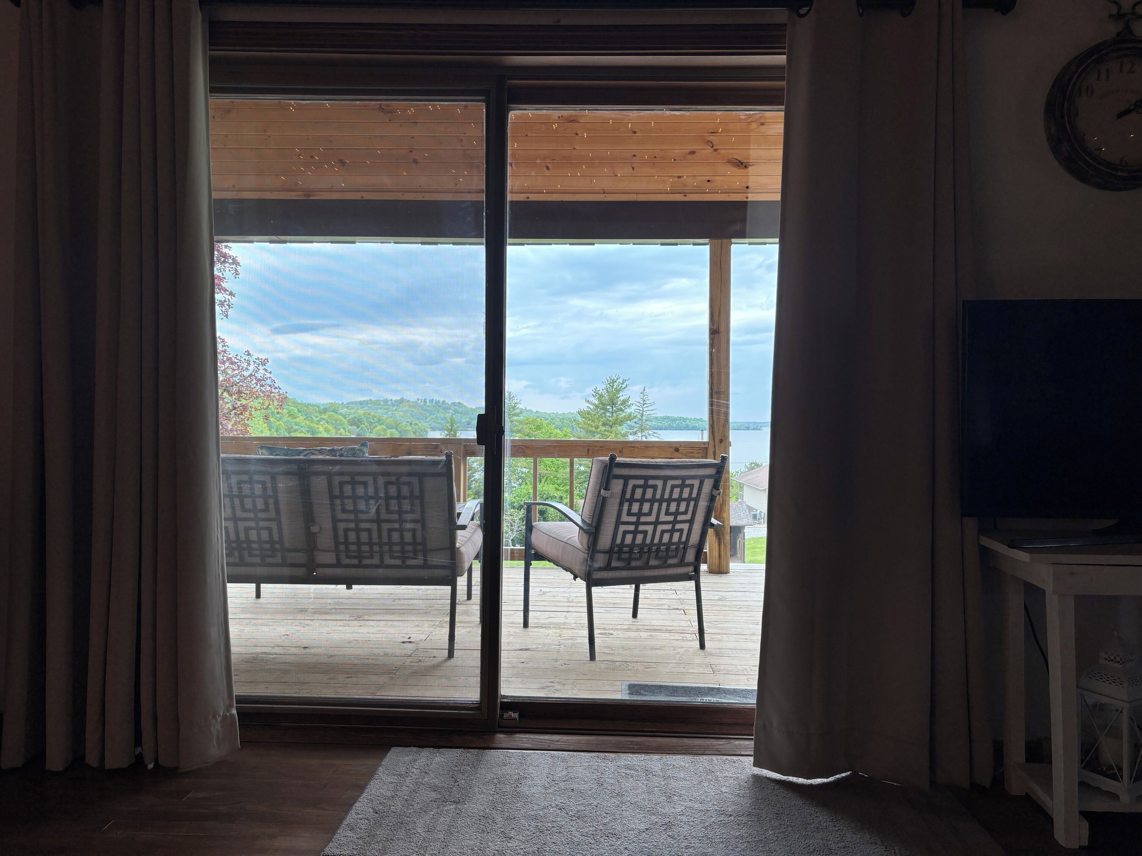 A room with a sliding glass door leading to an outdoor deck with two chairs and a table.