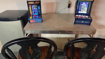 Zwei Spielautomaten auf einem Tisch, davor Stühle.