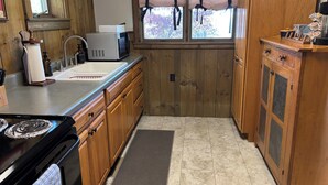 A kitchen with wooden cabinets, a stainless steel sink, a microwave, and a stove.