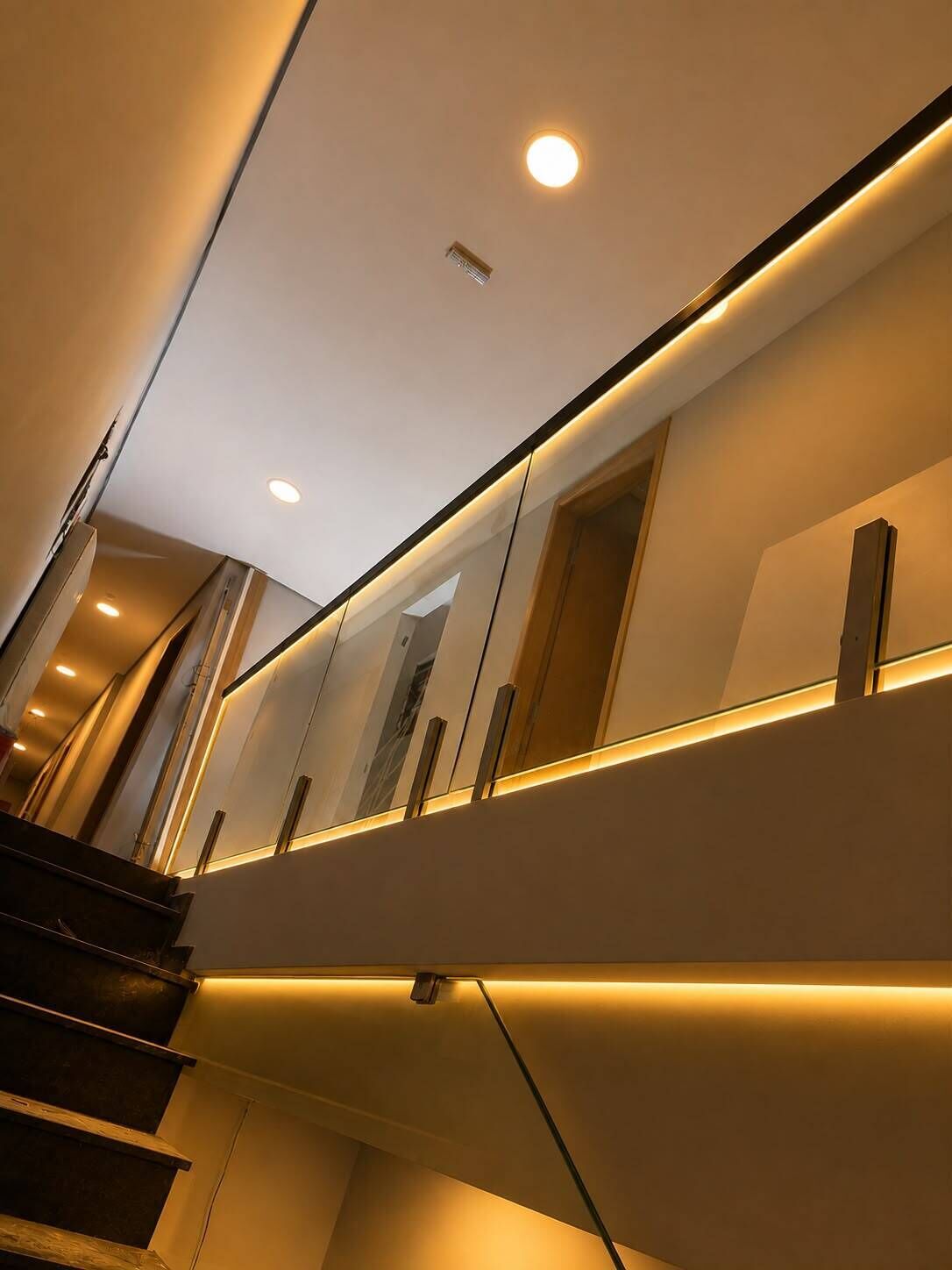 A modern staircase with a sleek design, featuring a handrail and a light fixture on the wall.