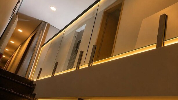 A modern staircase with a sleek design, featuring a handrail and a light fixture on the wall.