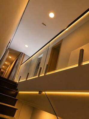 Un escalier moderne au design épuré, doté d’une main courante et d’un luminaire fixé au mur.