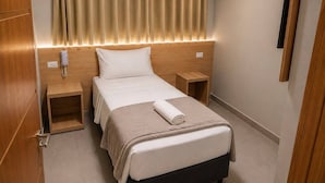 A hotel room with a bed, bedside tables, a telephone, and a curtain.