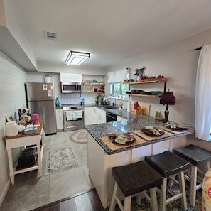A modern kitchen with white cabinetry, a central island with stools, a built-in oven, and a microwave. - Cozy 3-bedroom home near KSU, Braves and Lake Point SPorts Complex (Marietta)