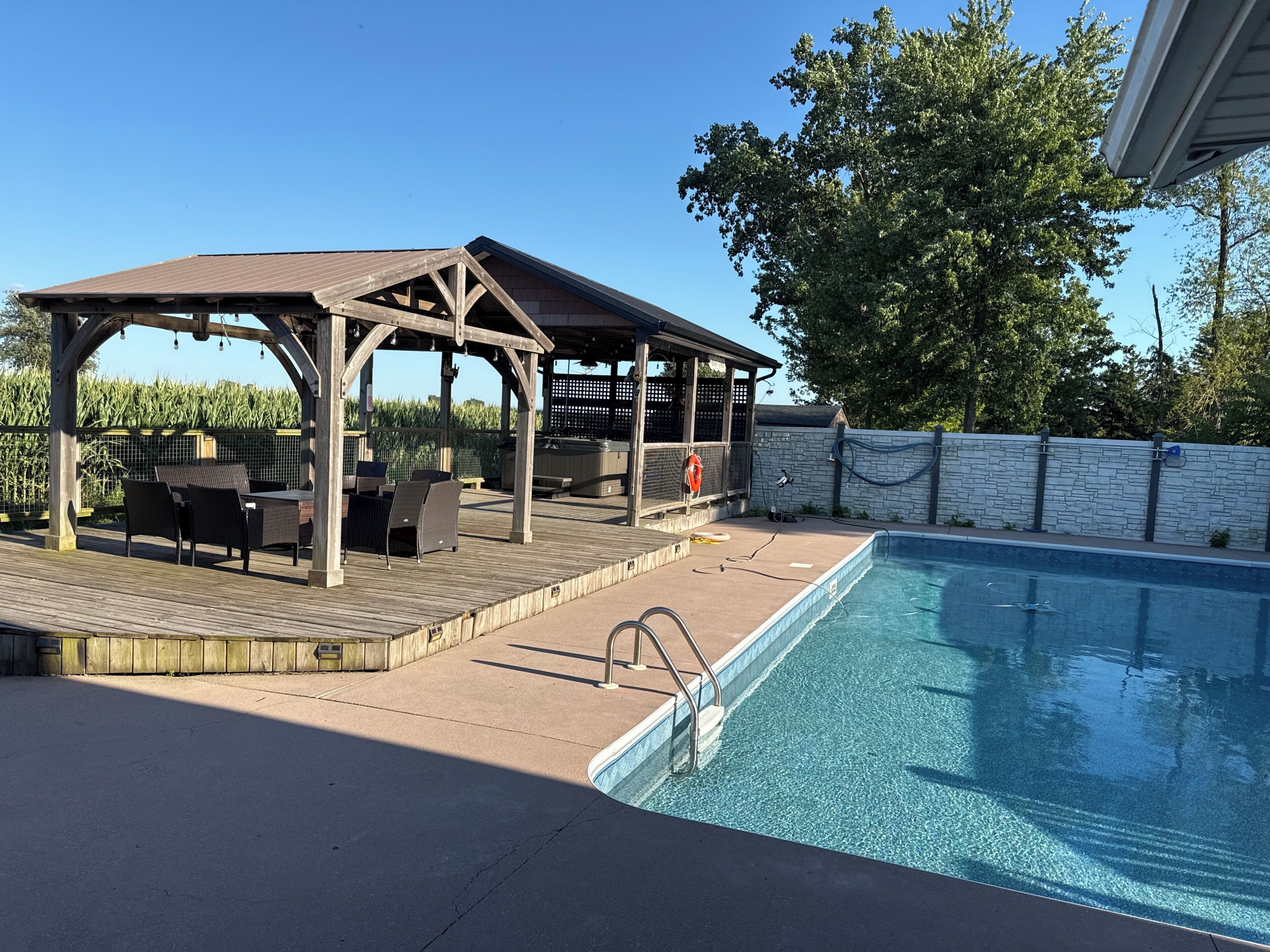 Un área de piscina con muelle de madera, mobiliario exterior y jacuzzi.