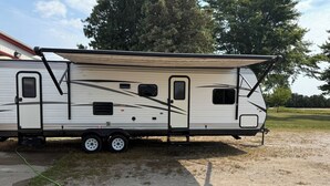 A recreational vehicle parked on a gravel surface with a trailer attached, featuring multiple windows and a door. - After beaten path.
Camper with great amenities (Lakeshore)