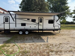 A recreational vehicle parked on a gravel surface with a trailer attached, featuring multiple windows and a door. - After beaten path.
Camper with great amenities (Lakeshore)
