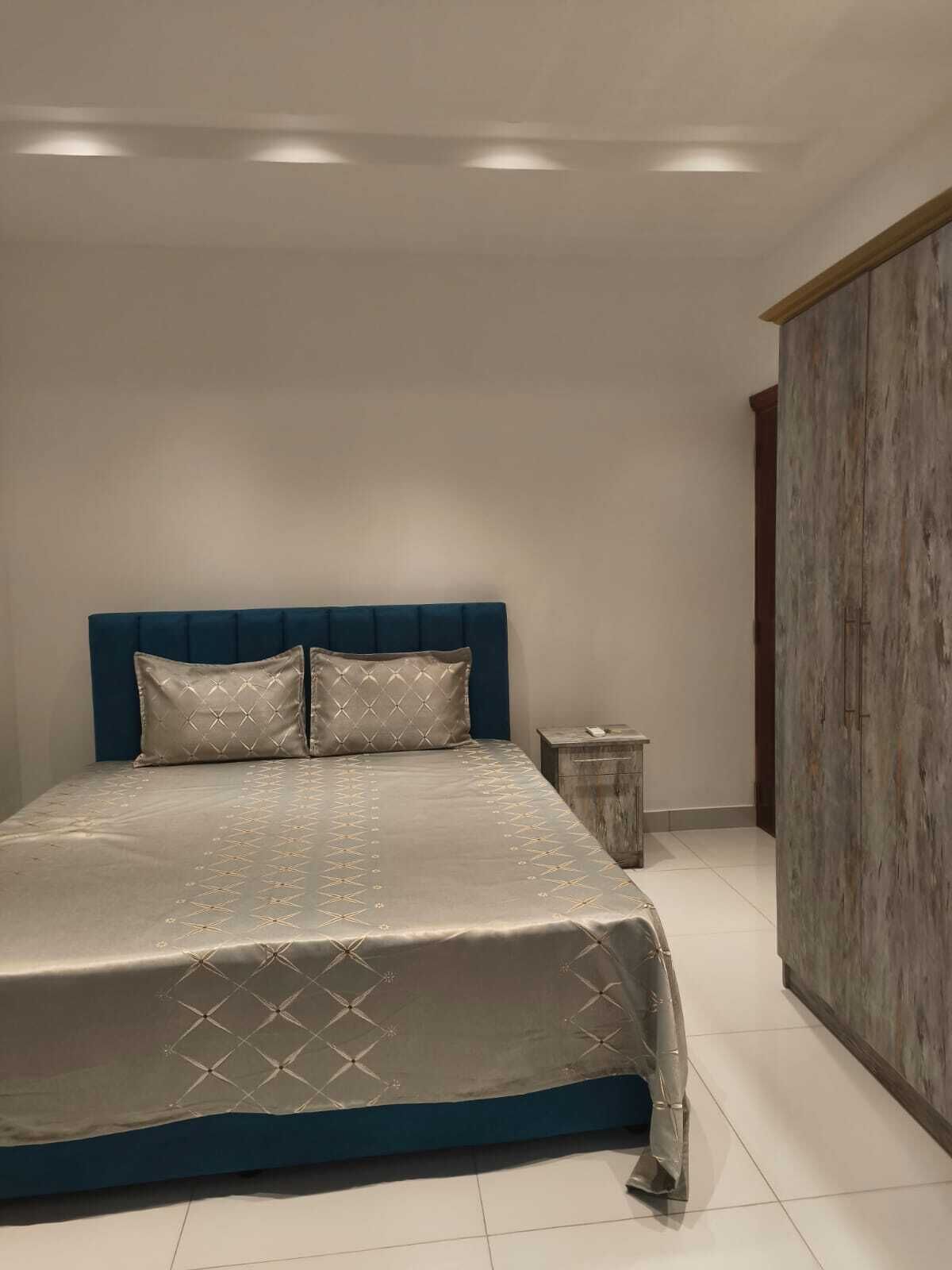 Un dormitorio con una cama grande, una mesita de noche y un armario.