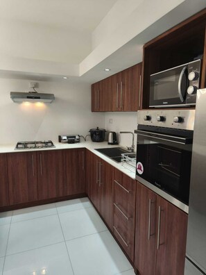 A modern kitchen with dark wooden cabinets, stainless steel appliances, and a white countertop. - Horizon view (Flic en Flac)