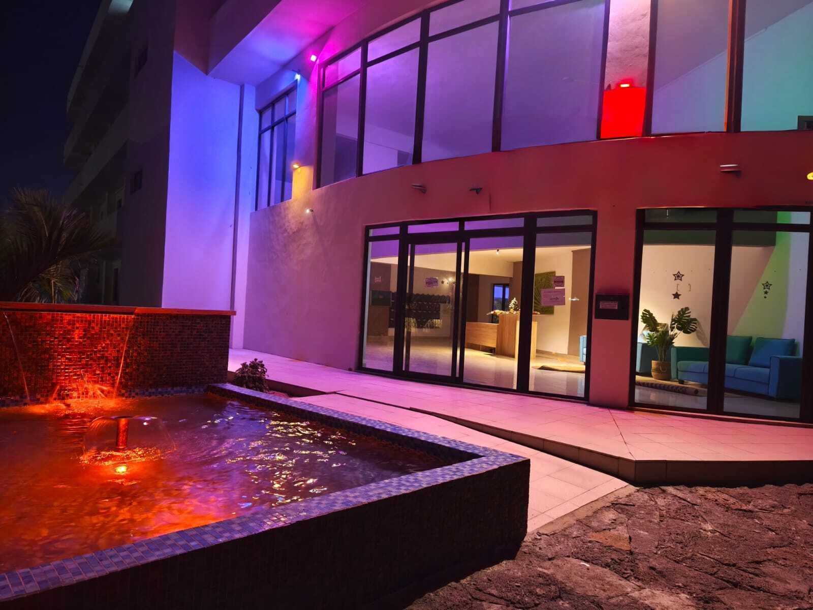 Ein modernes Hotelgebäude mit Schwimmbad, großen Fenstern und einer Rezeption.