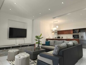 A modern living room with a flat-screen TV, a sofa, ottomans, and a coffee table. - Horizon view (Flic en Flac)