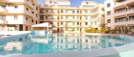 A swimming pool surrounded by multi-story buildings with balconies.