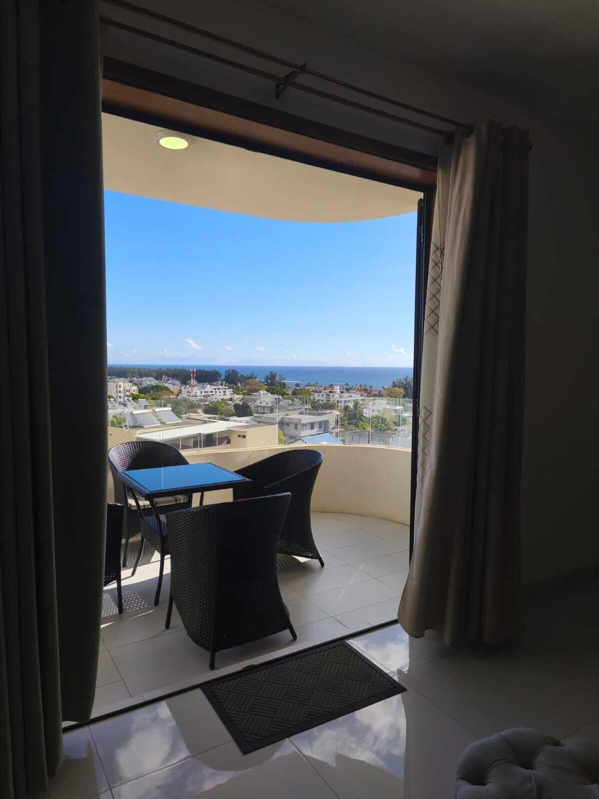 A balcony with a table and chairs, a view of the cityscape, and a clear sky.
